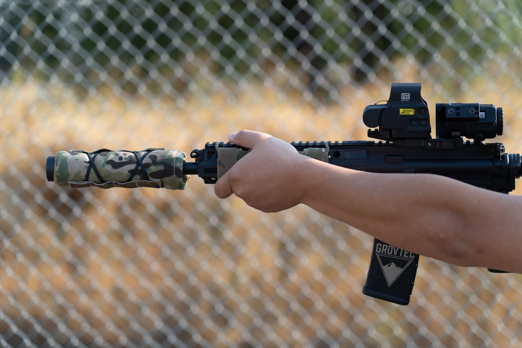 a person holding a camera in front of a fence 