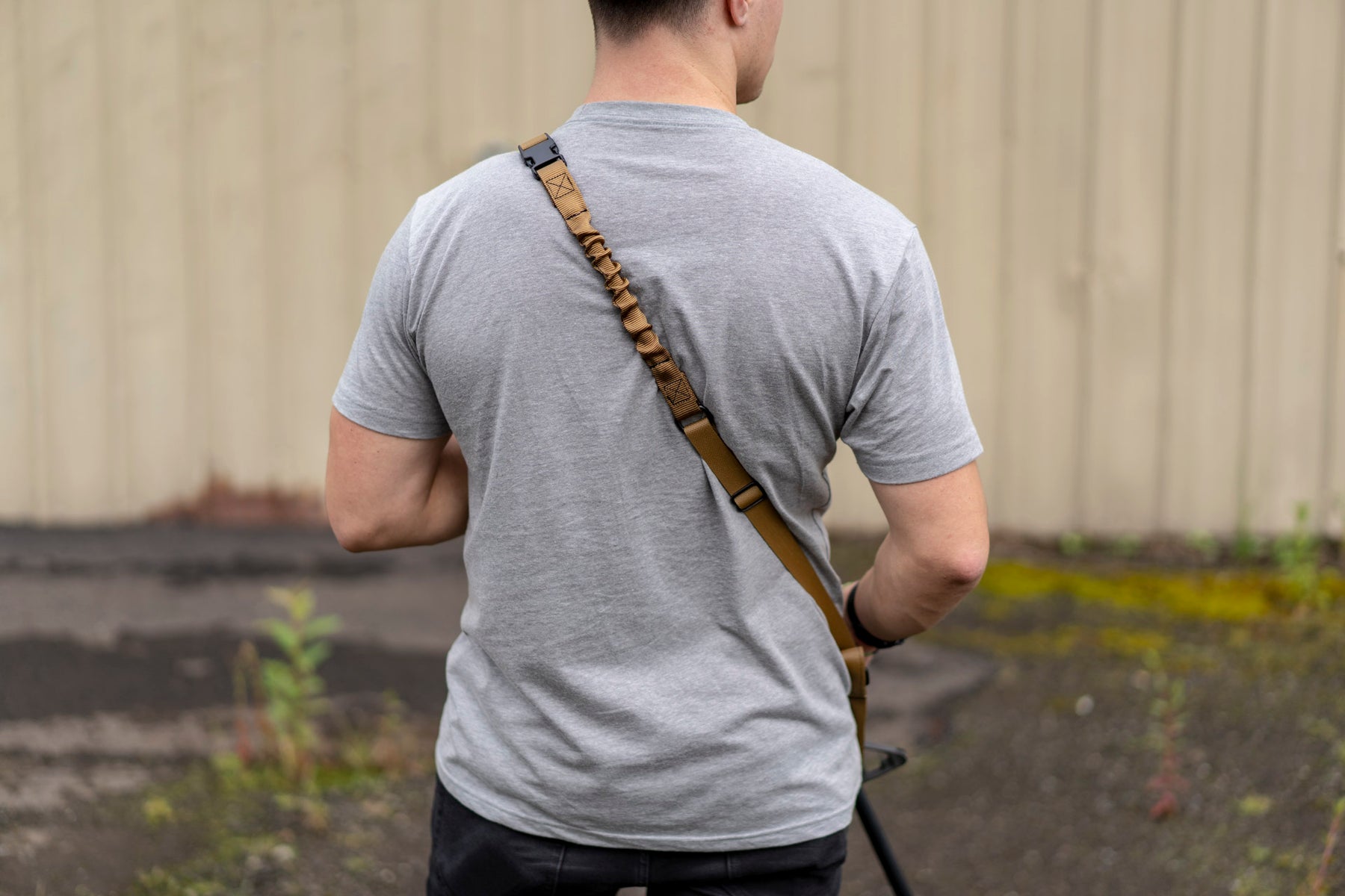 a man standing on a sidewalk holding a tennis racquet 